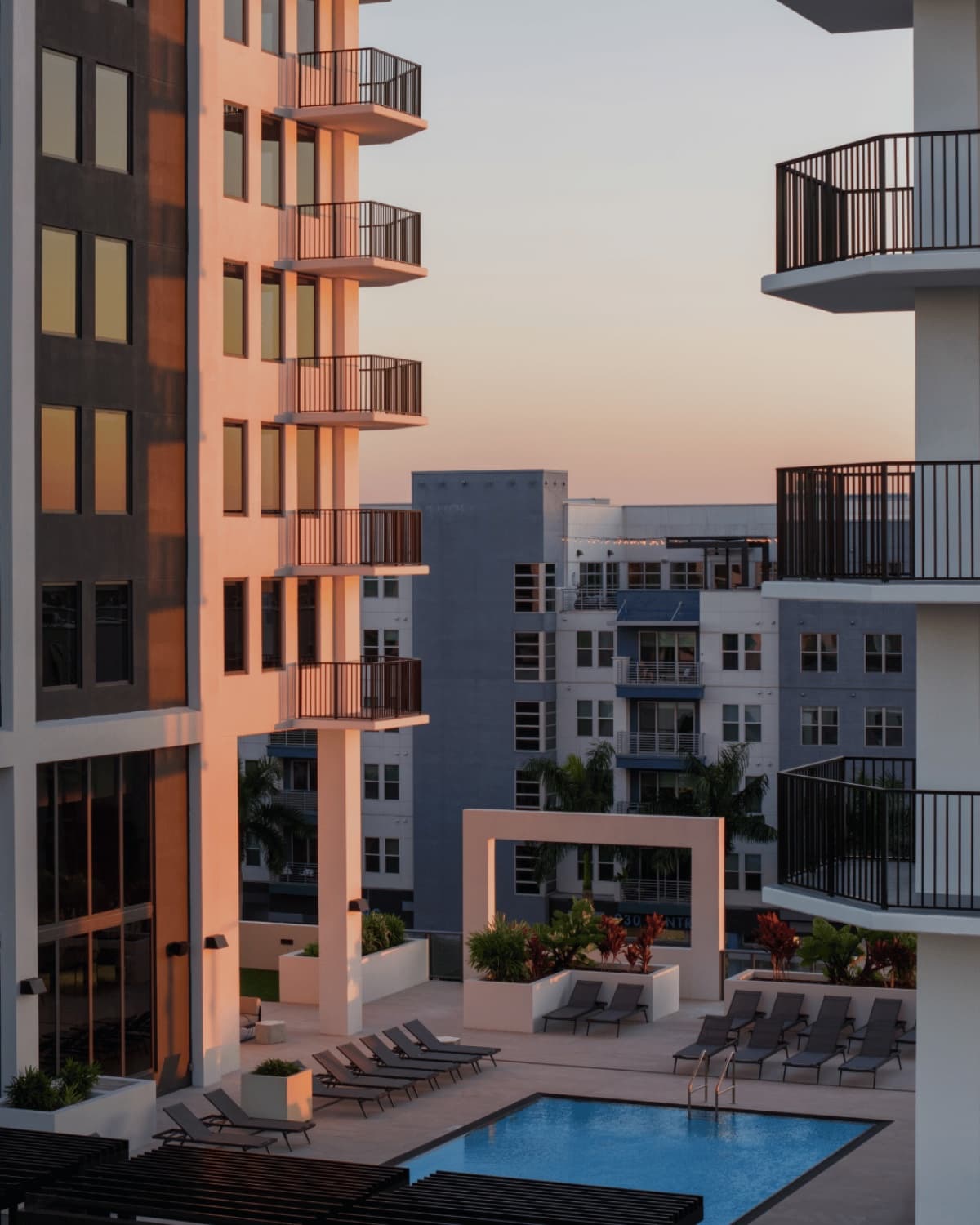 Mid-rise residential building at sunset with pool deck below