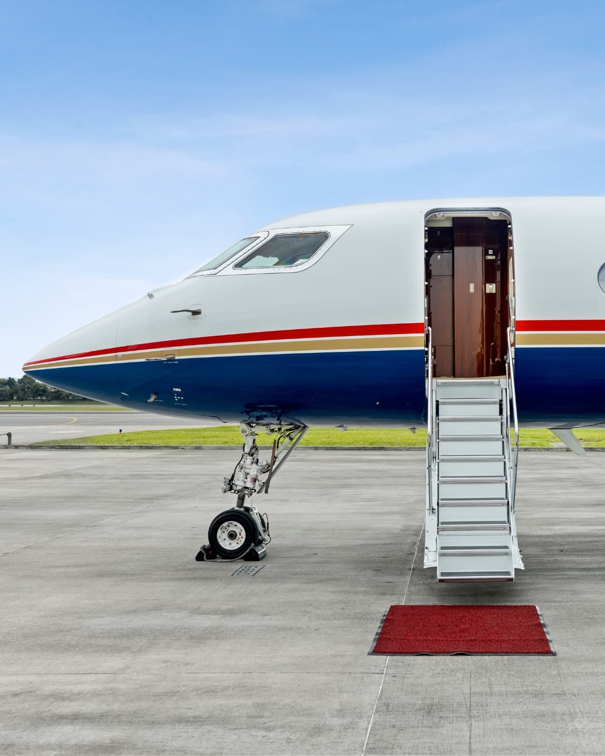 Private jet on tarmac with airstairs down and red carpet