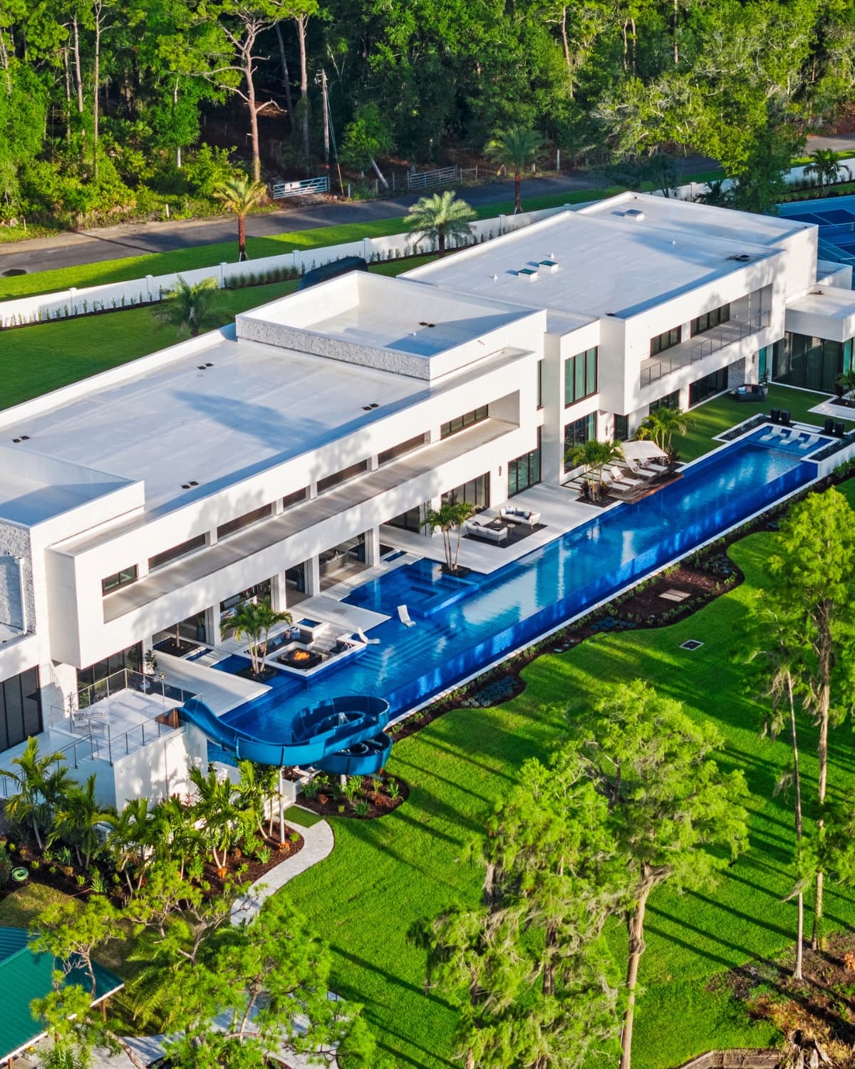 Luxury estate at night — illuminated pool, waterfall feature, dramatic landscape lighting