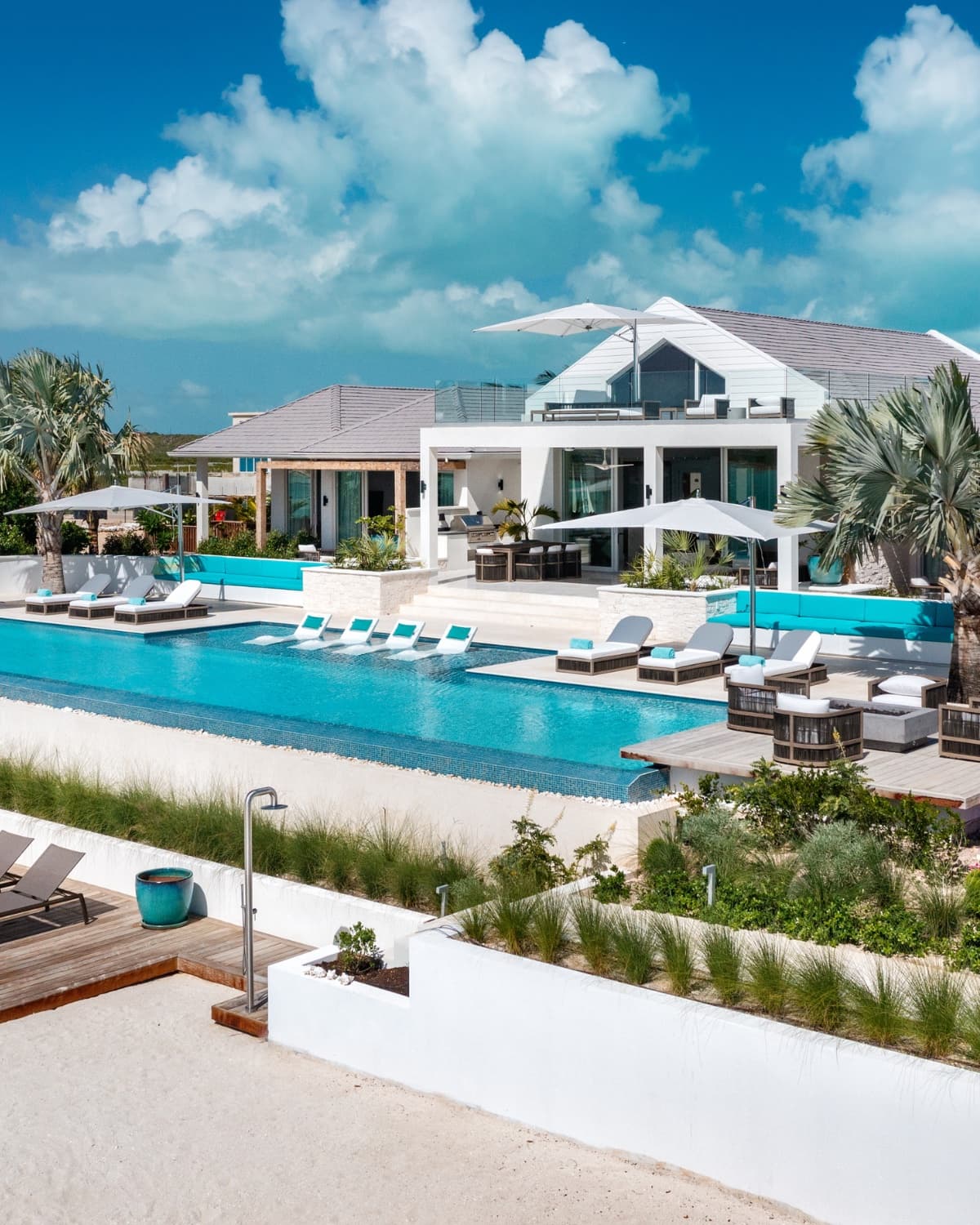 Eye-level view of a Caribbean luxury villa — infinity pool, loungers, dramatic sky