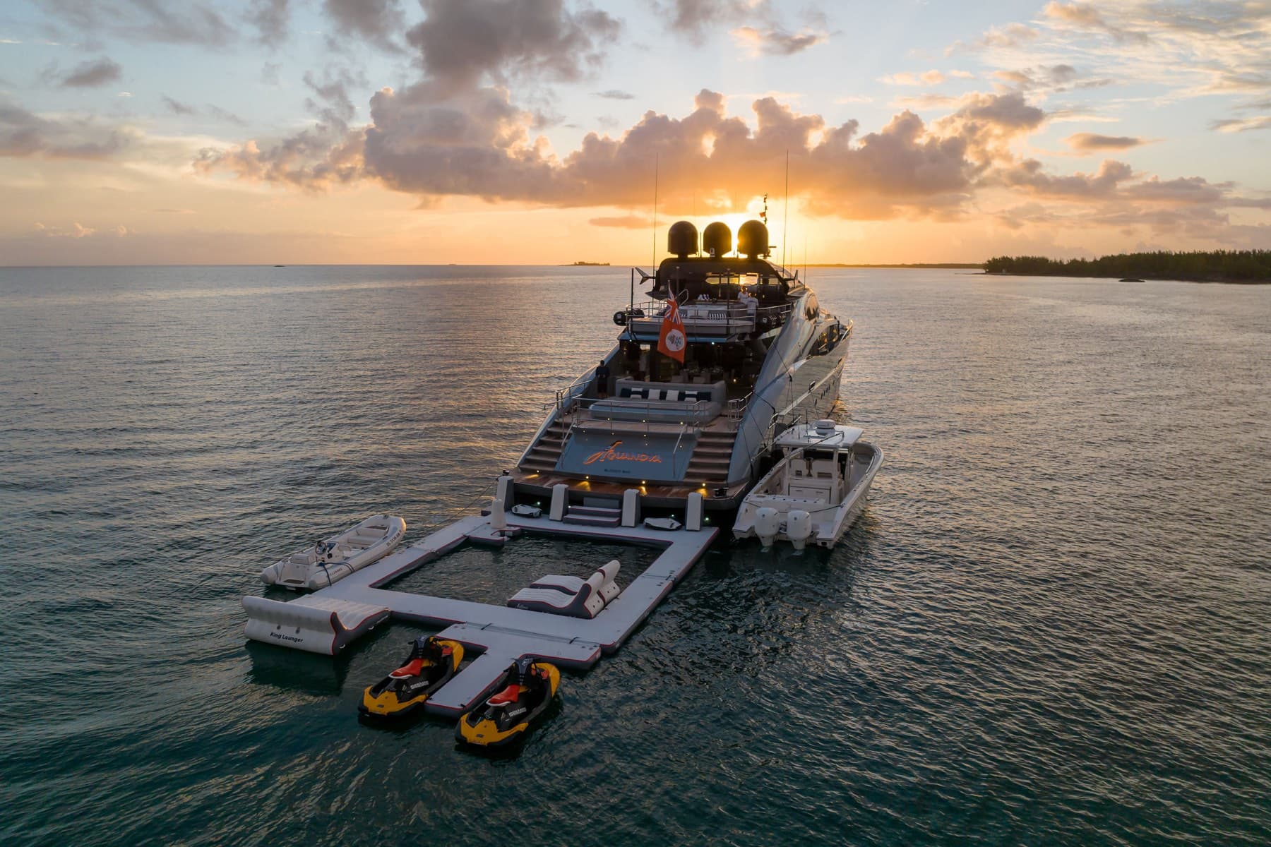 Aerial of yacht stern at sunset with sea pool and jet skis
