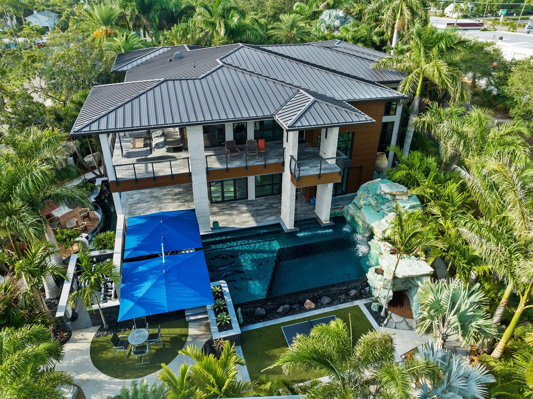 Aerial view of tropical modern estate with lagoon pool amid lush palms