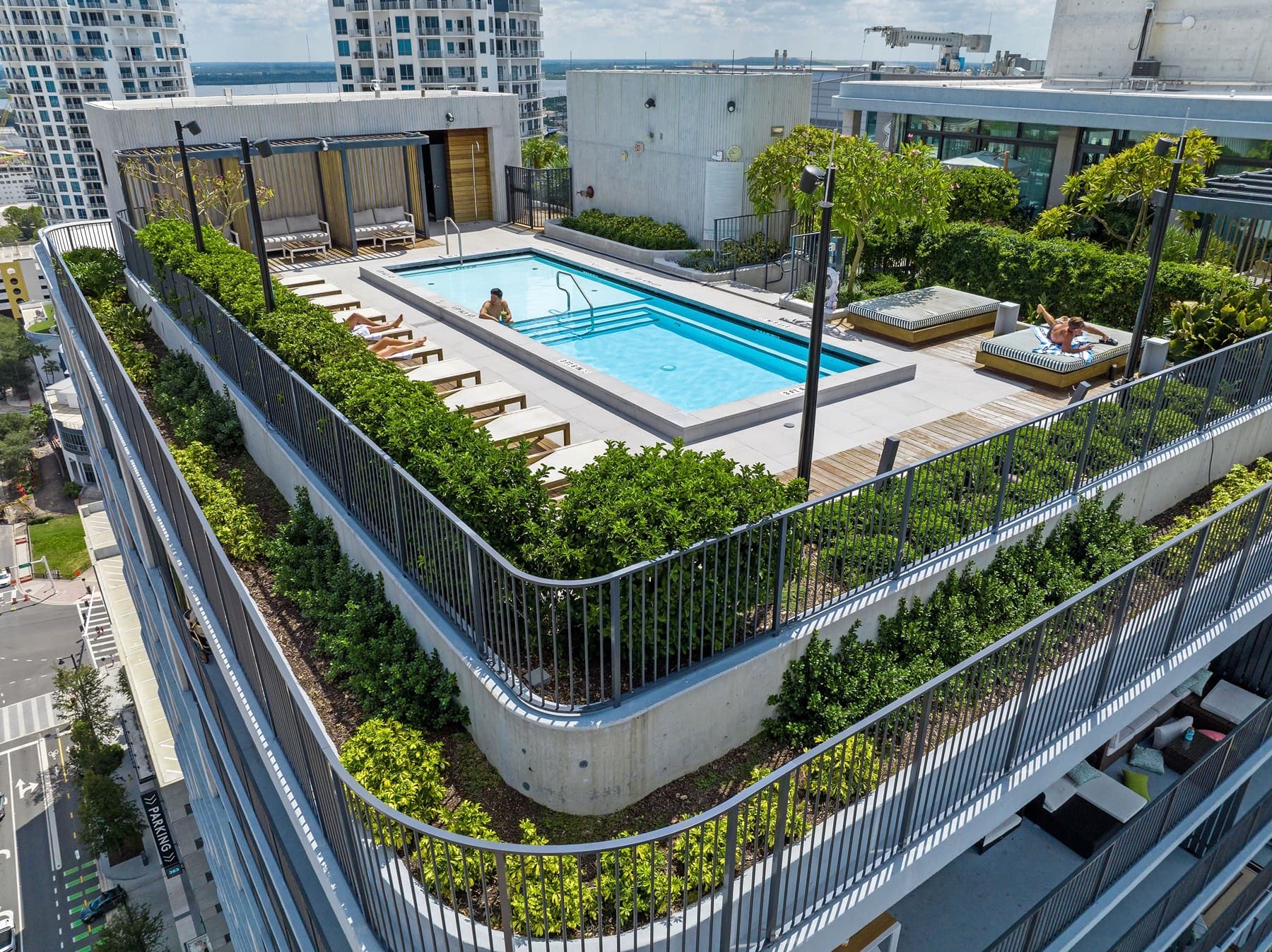 Aerial of landscaped rooftop pool deck atop downtown residential tower