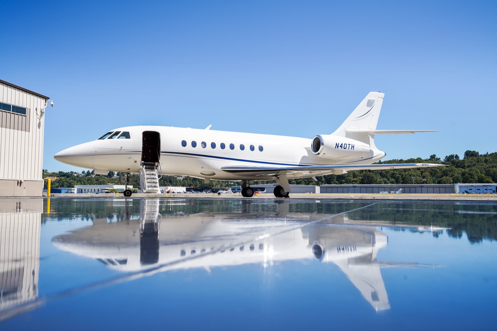 Falcon 2000EX in full mirror reflection on a wet ramp outside the hangar