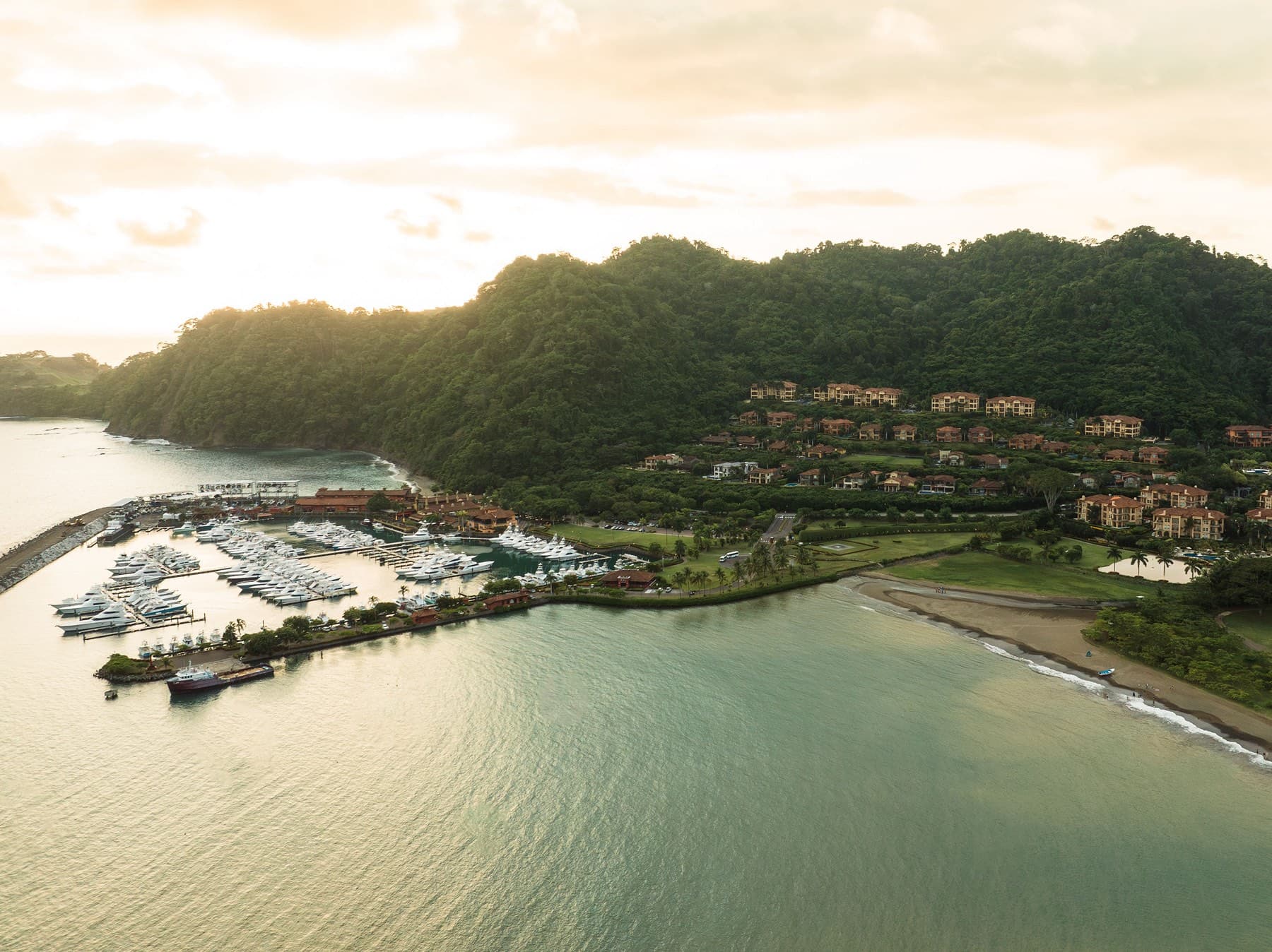 Sunrise aerial of Los Suenos marina, jungle hillside, and Pacific coastline