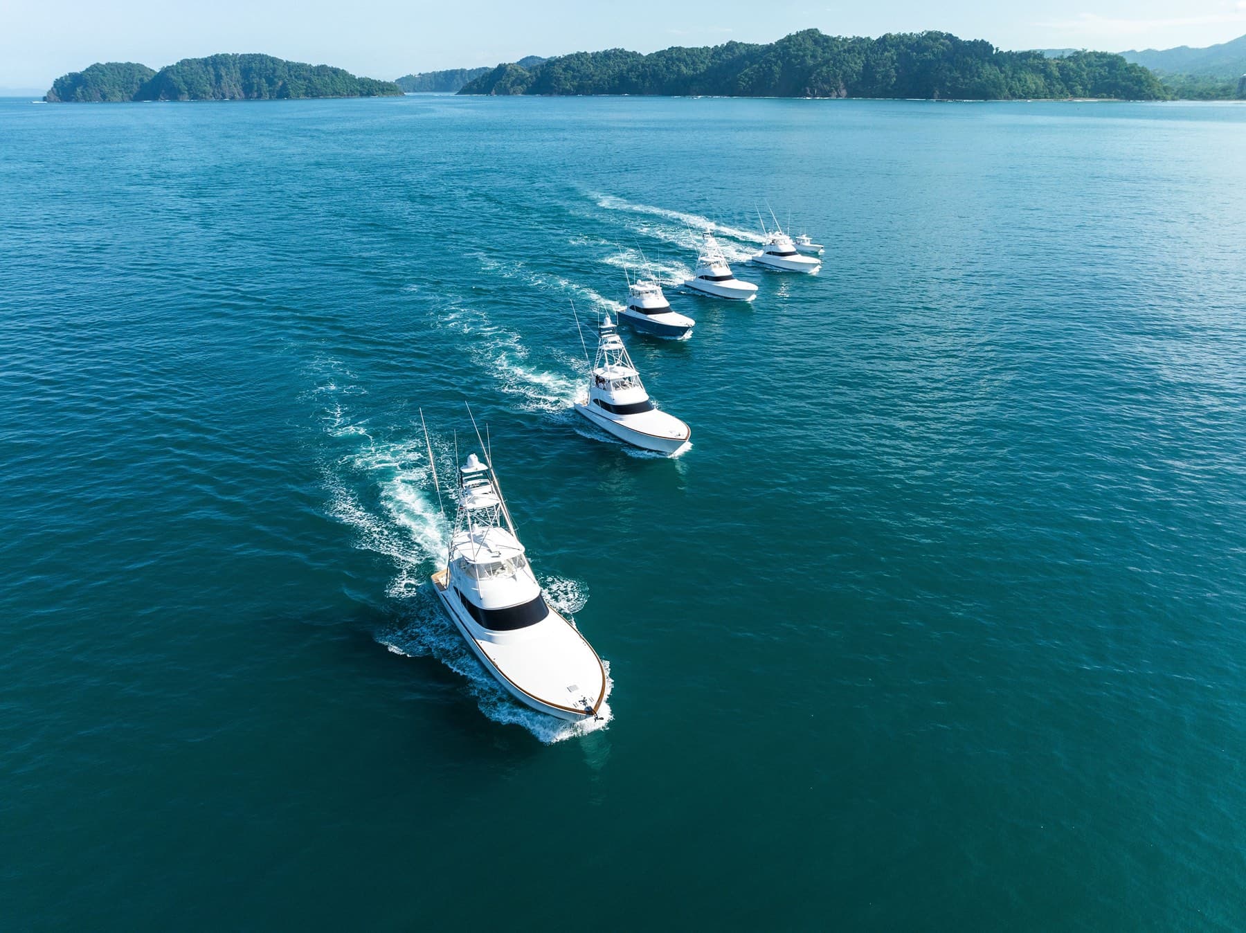 Five sportfishing yachts running in formation across deep blue water