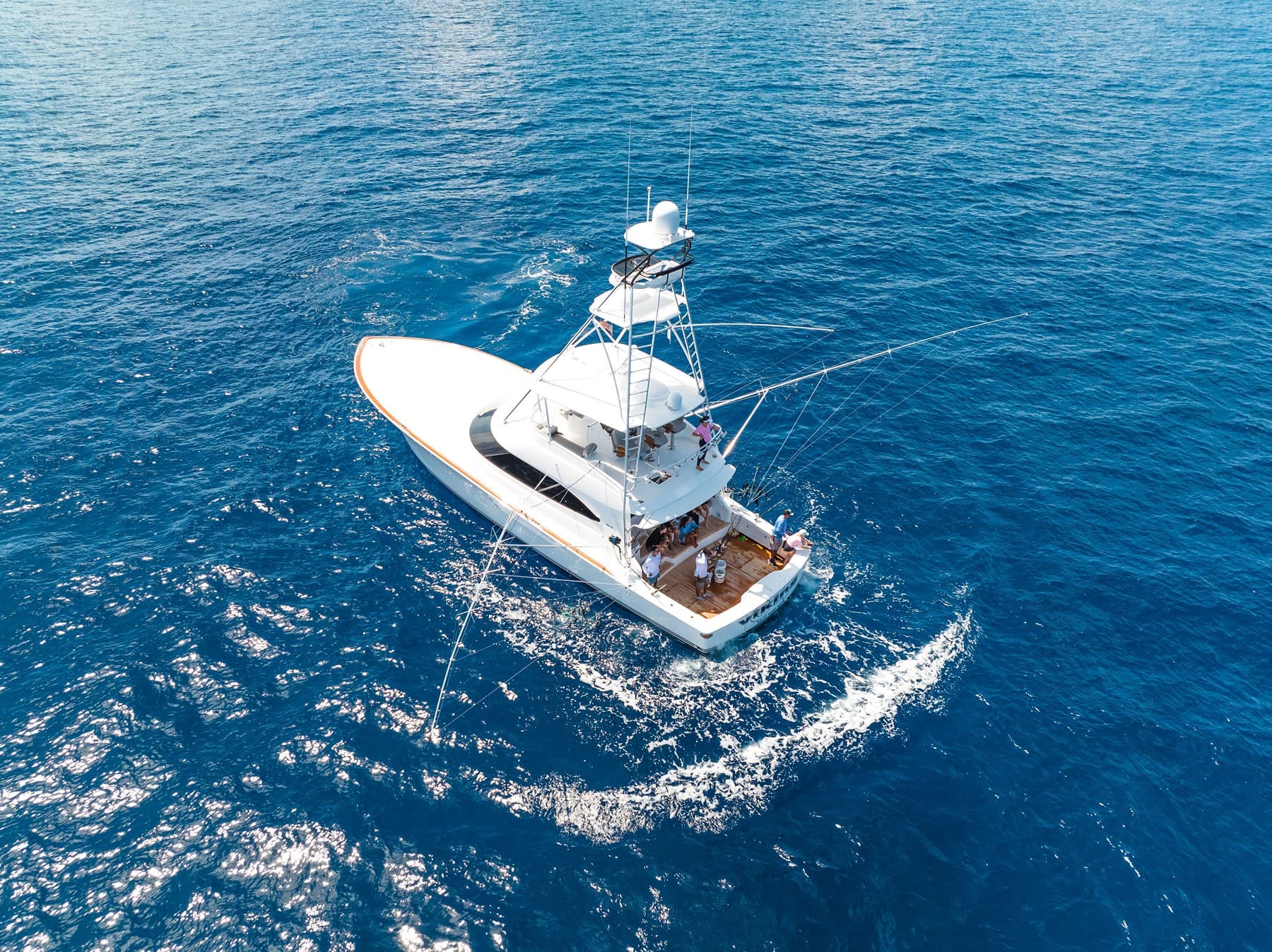 Top-down aerial of sportfish yacht carving a wake offshore