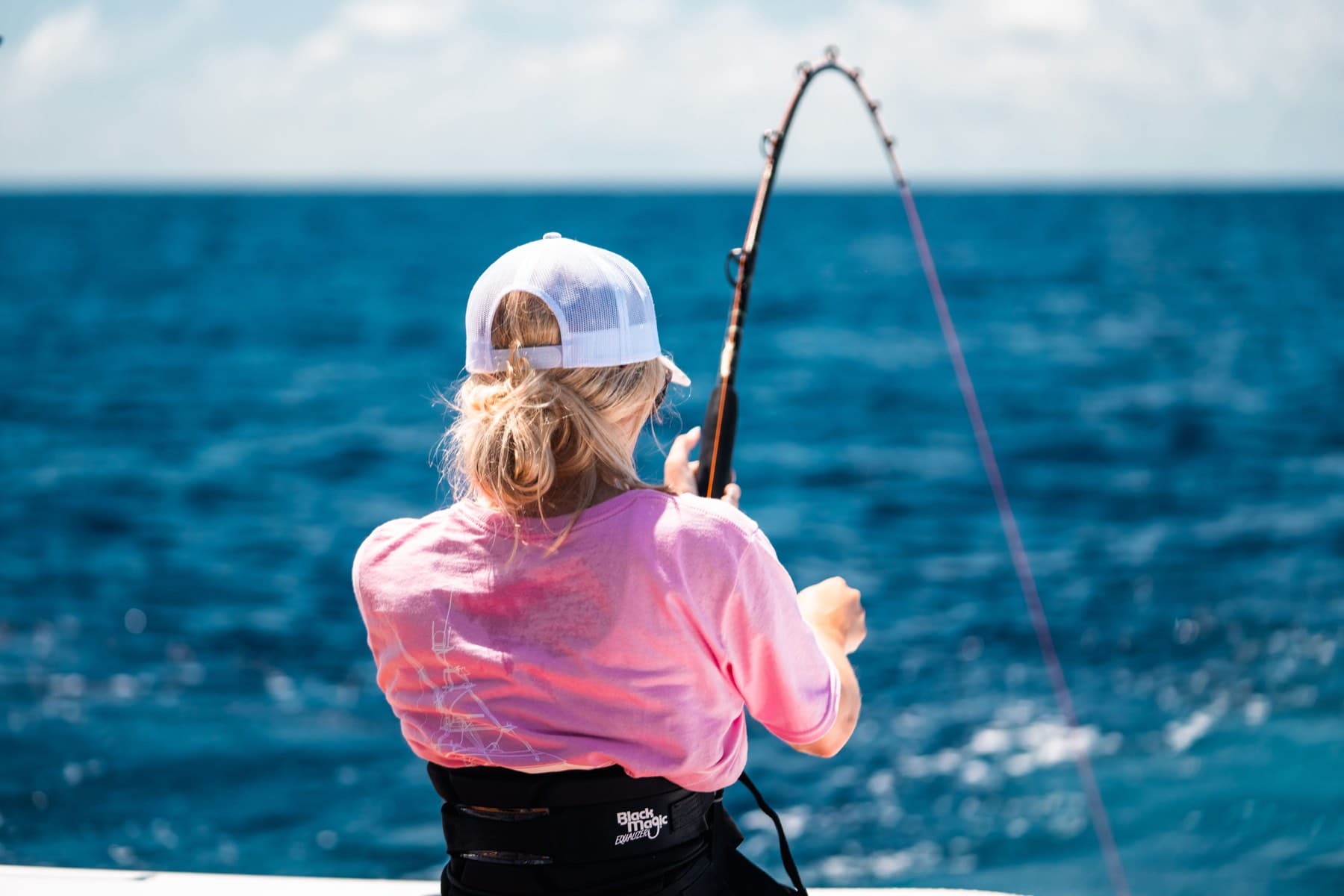 Angler bending a rod against vivid blue offshore water