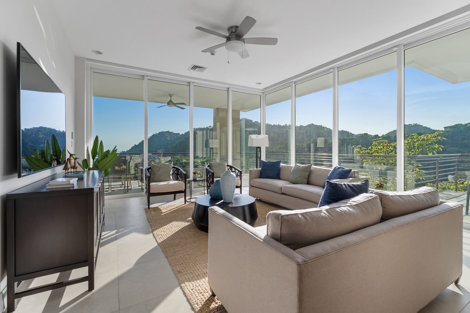 Bright villa living room with floor-to-ceiling windows and jungle views