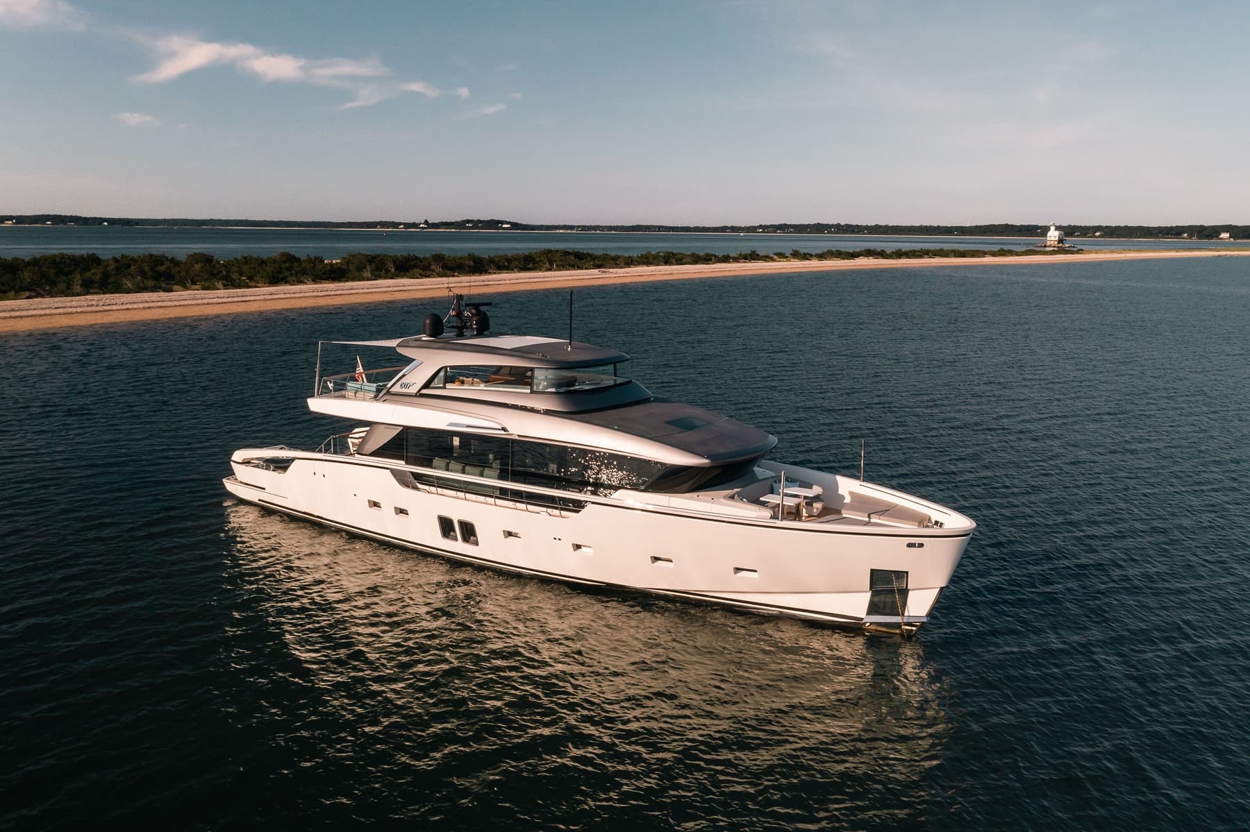 Aerial of motor yacht anchored off a sandy spit in golden light