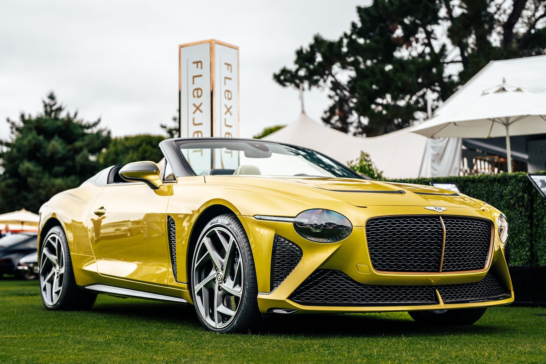 Yellow Bentley Bacalar roadster displayed beside Flexjet event tower
