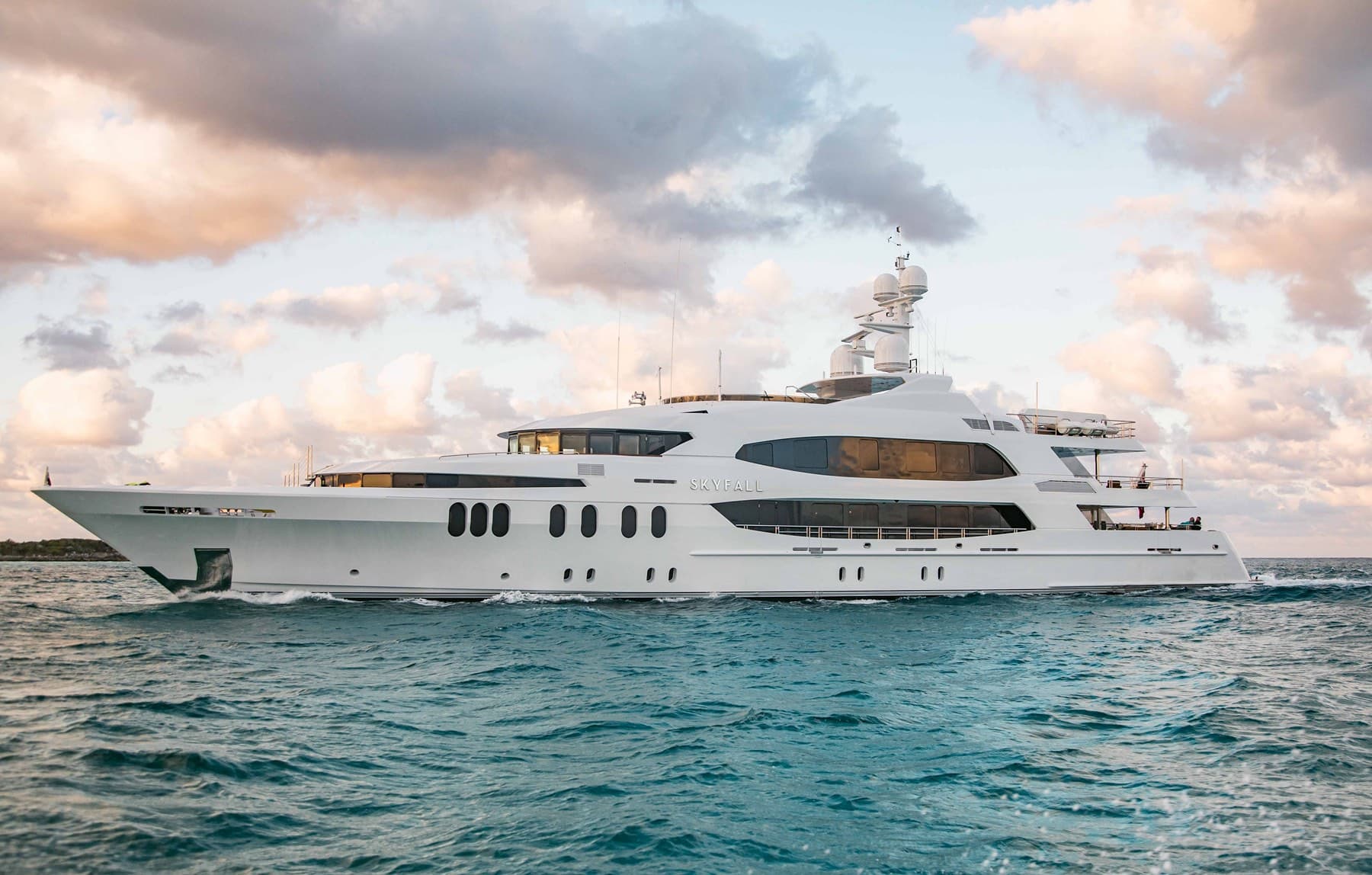 Superyacht Skyfall underway at dusk beneath pastel pink clouds — Surroundings Group studio production